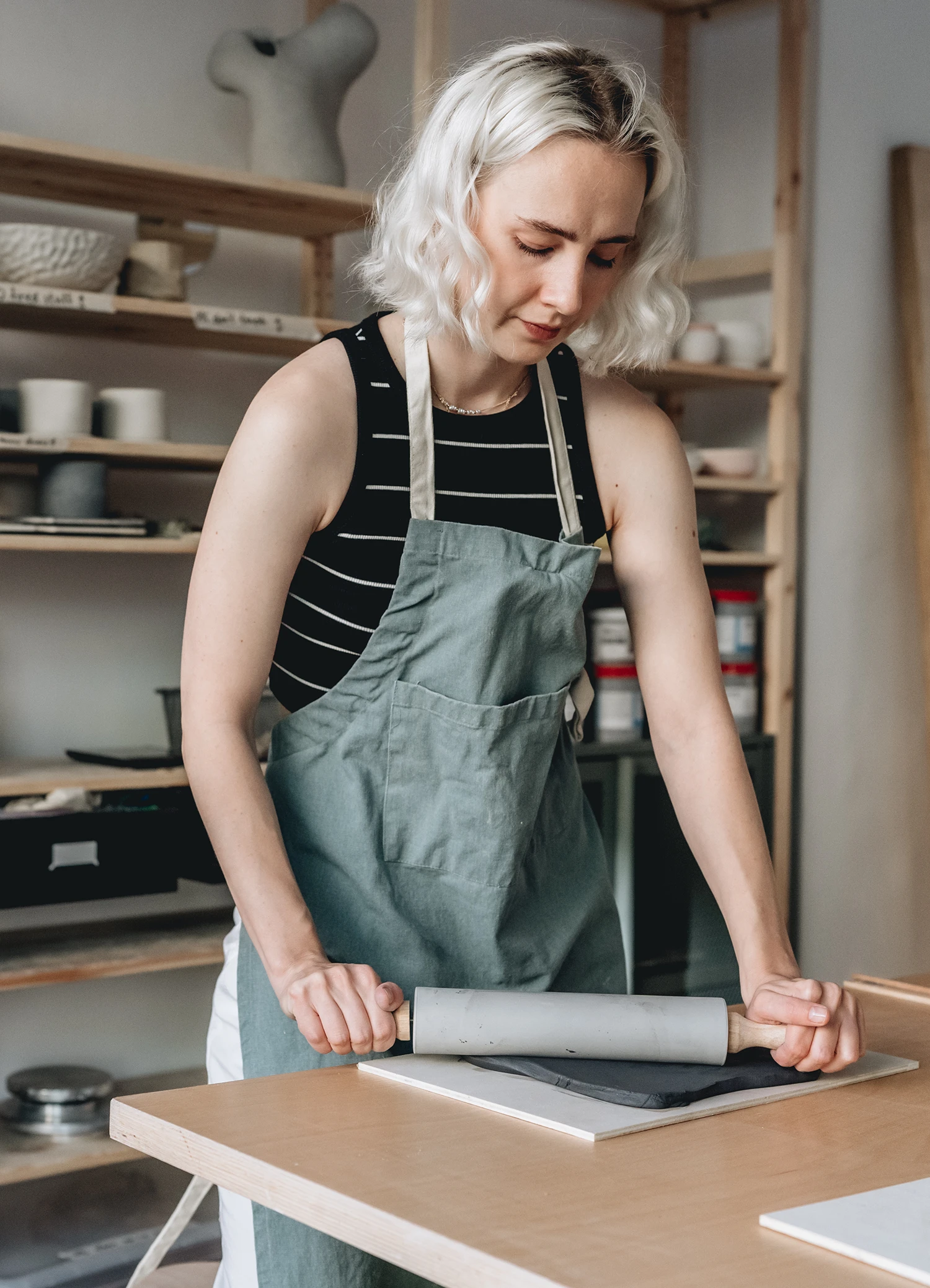 Business Reportage: Eine junge Frau rollt Ton zu einer dünnen Fläche aus