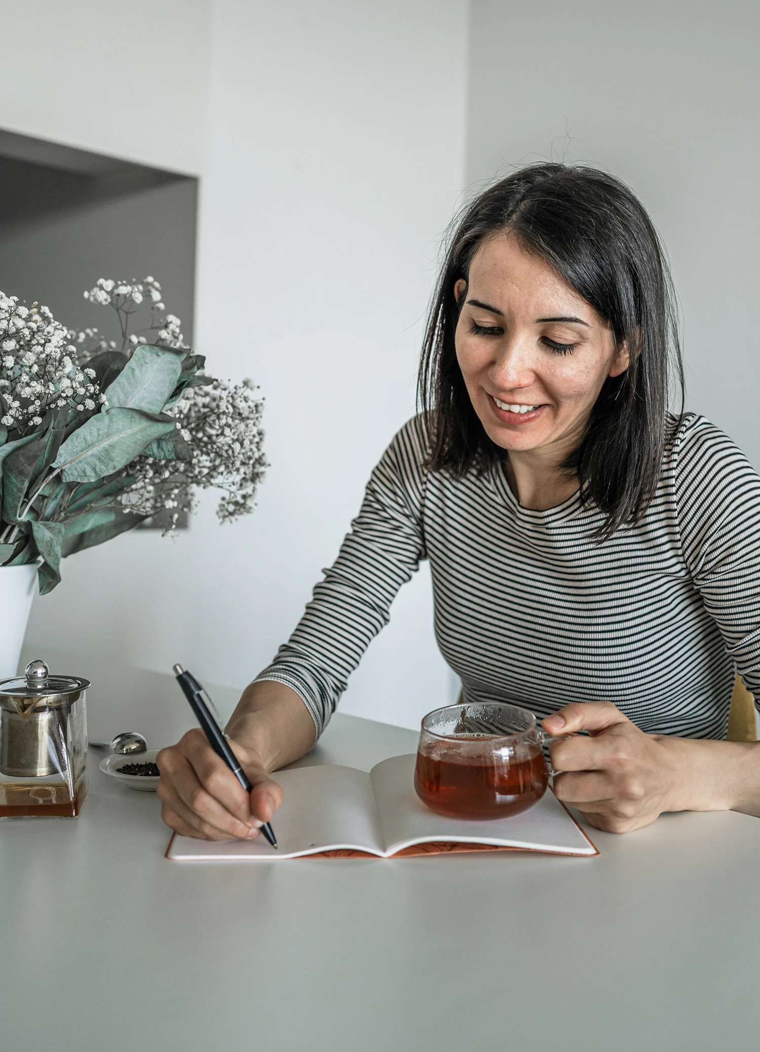 Personal Branding Foto einer Frau, die in ein Notizbuch schreibt und eine Tasse Tee trinkt